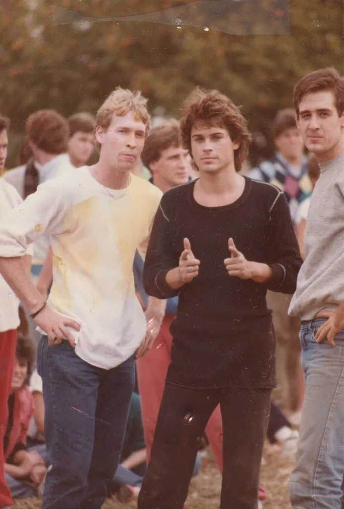 Howard Schacter in a white and yellow shirt and jeans next to Rob Lowe in black shirt and pants