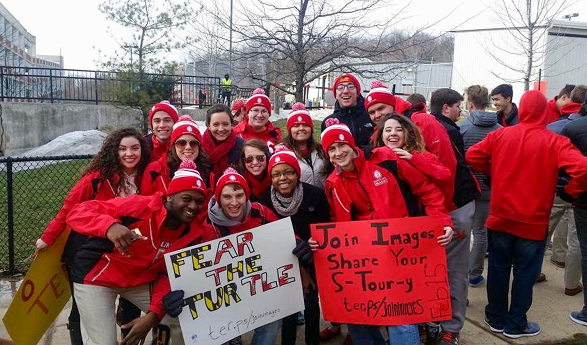 Dante Evans and Maryland Images students holding signs that say Fear the Turtle and Join Images