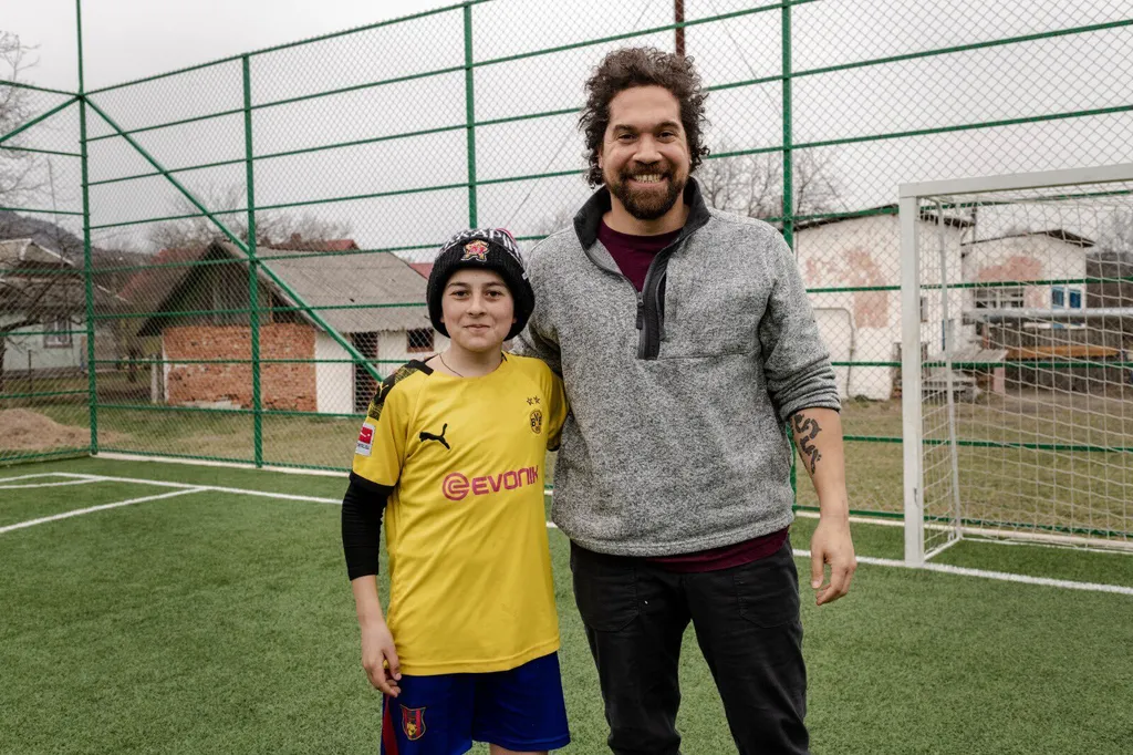 Robert Klemko with arm around young soccer player wearing UMD beanie