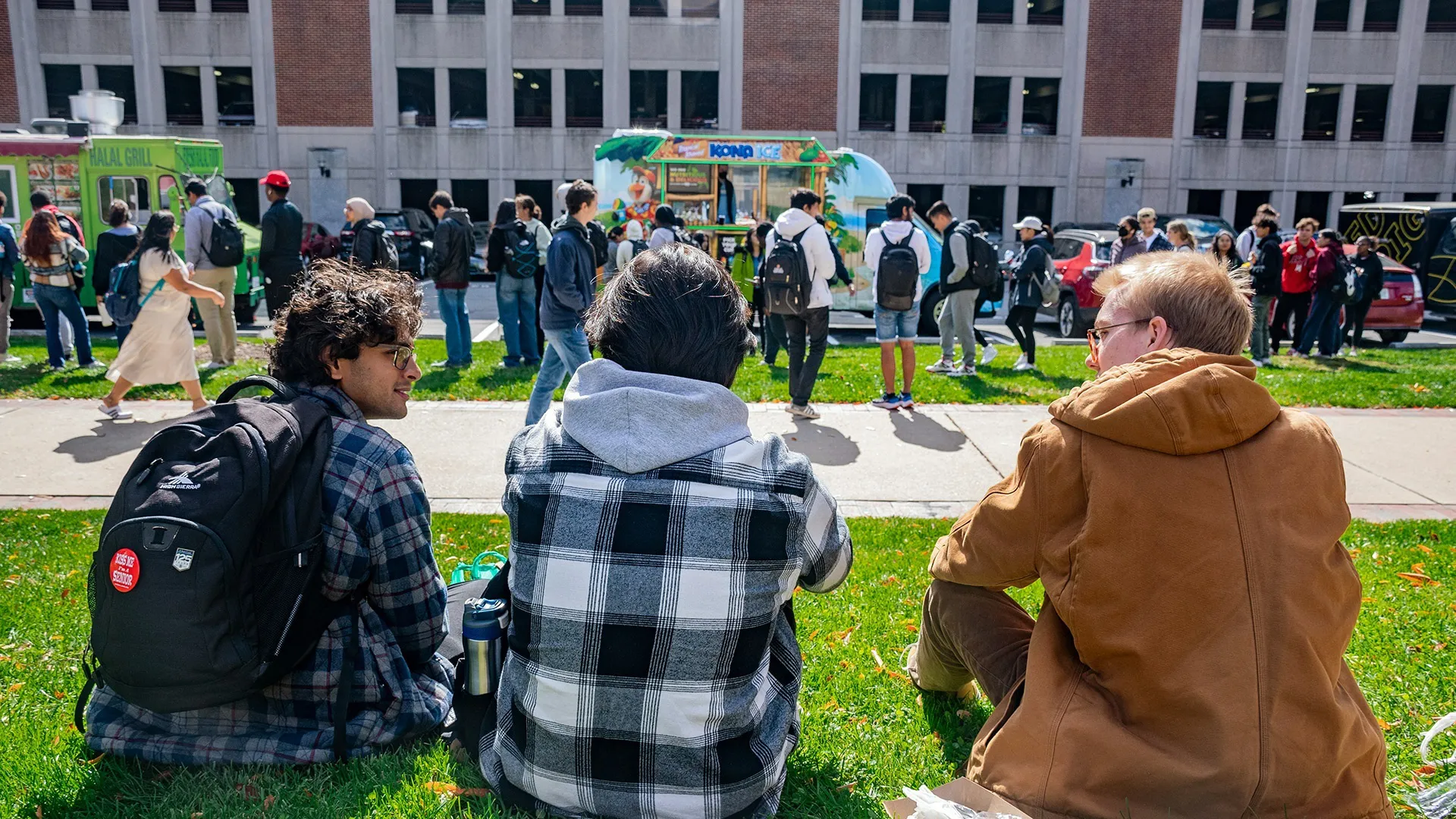 3 students sitting near a food truck