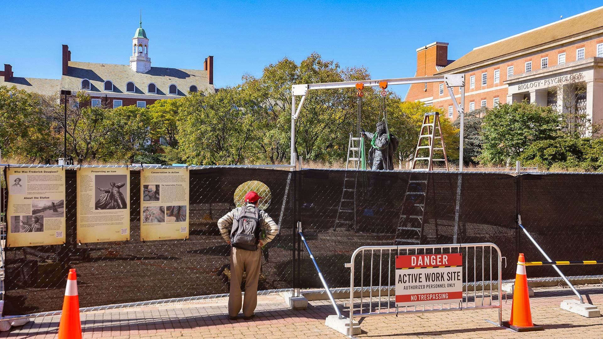 passerby watches as Frederick Douglass statue is removed from its pedestal for conservation