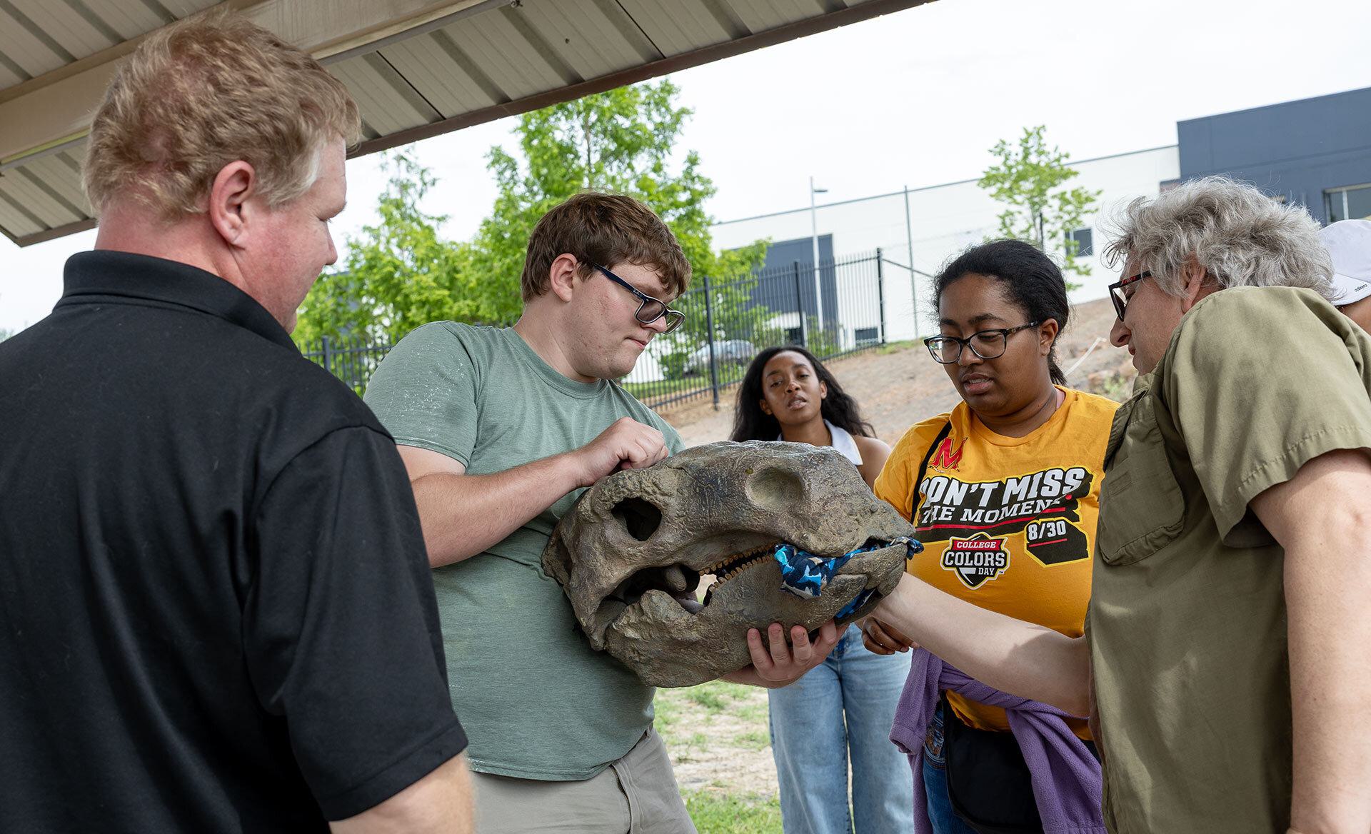 A student holds a model dinosaur fossil head