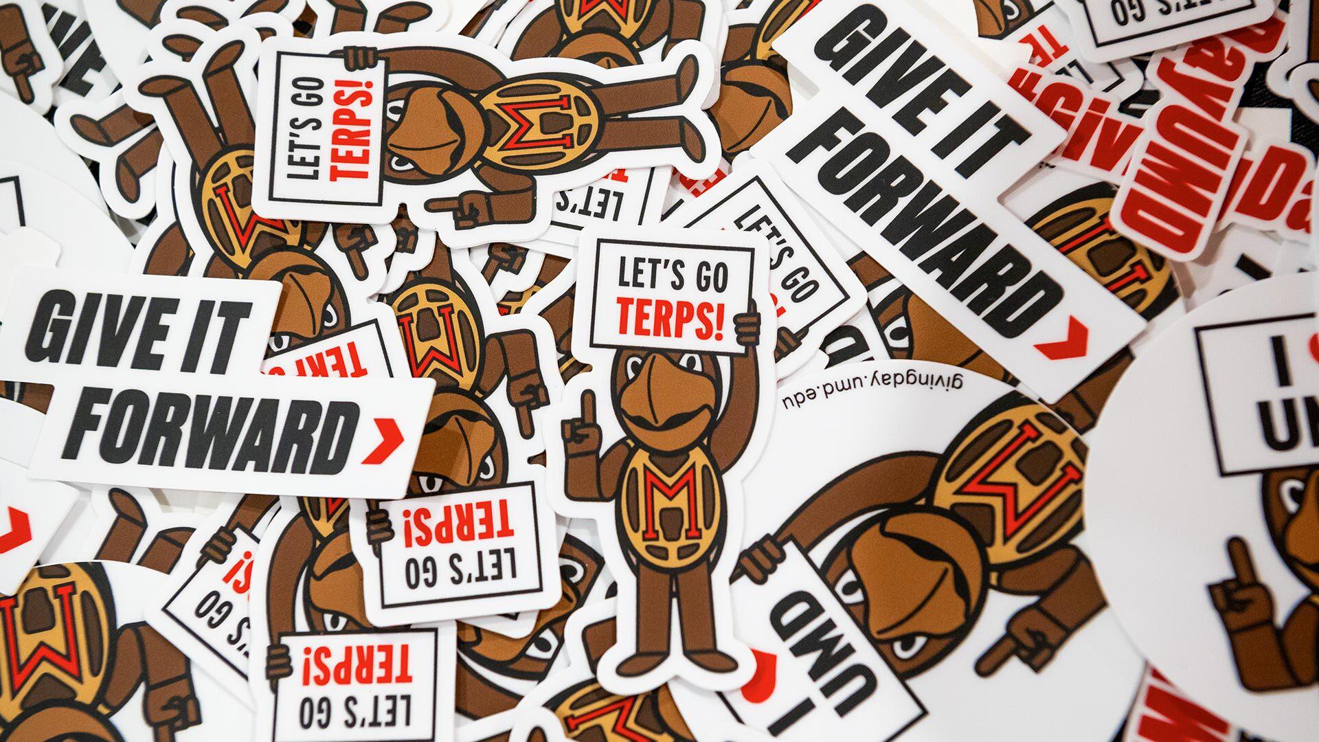 pile of Testudo stickers that say, "Give it Forward" and "Let's go Terps!"