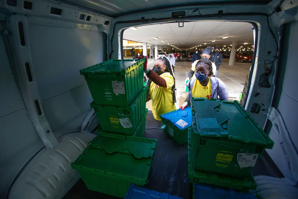 Volunteers load bins of donated canned goods into a van to transport them to the College Park Community Food Bank