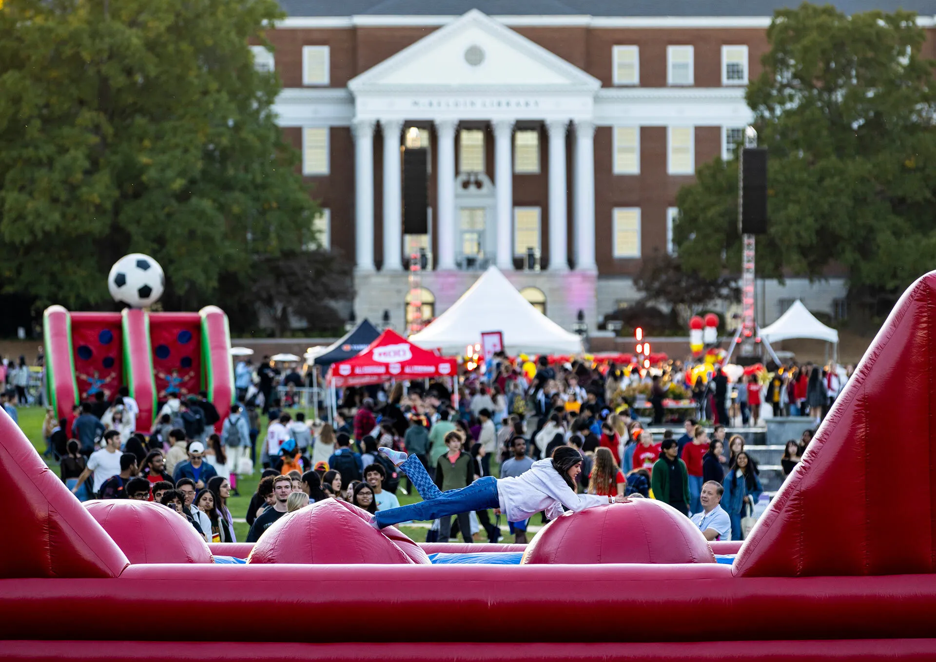 near a crowd, a person falls down on an inflatable obstacle course