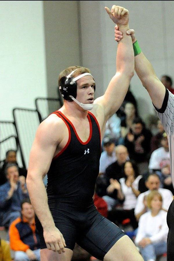 Male wrestler in singlet with arm held up by referee