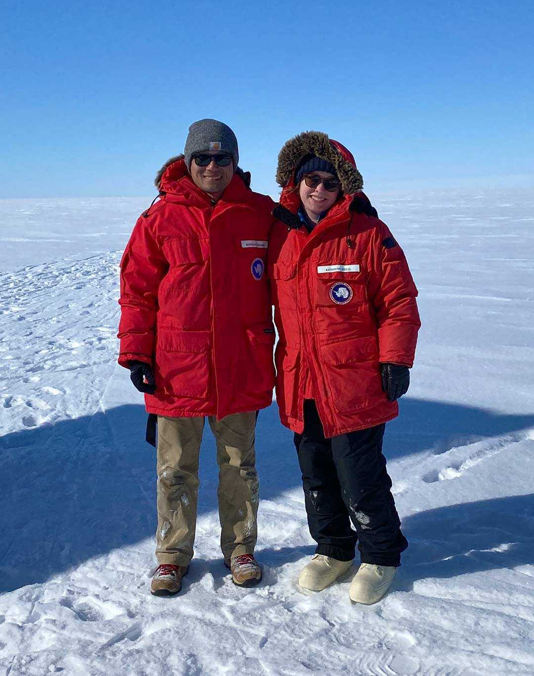 Two people in big red coats standing in the snow