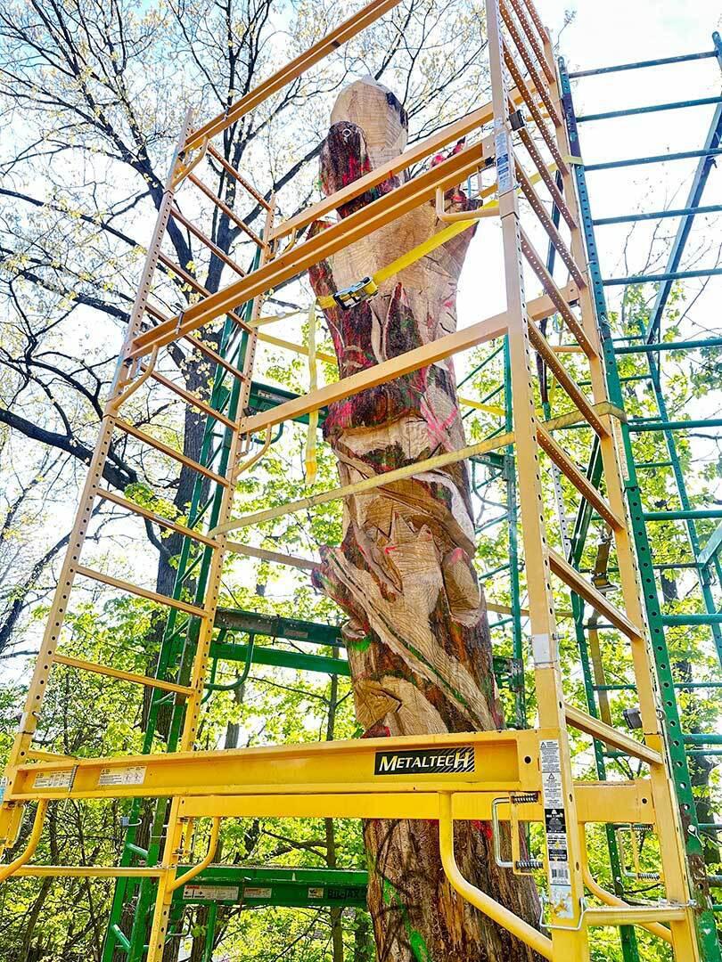 scaffolding surrounded tall wood sculpture in progress