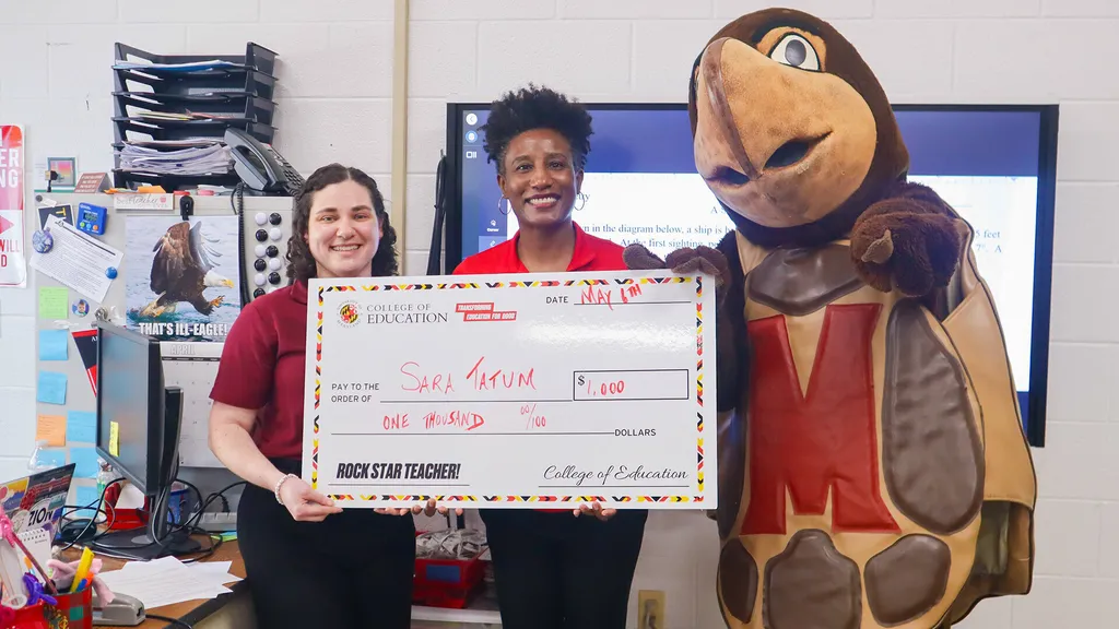Sara Tatum holds giant check with Kimberly Griffin and Testudo