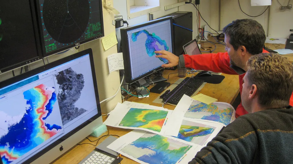 Guys look at charts and computer screens showing undersea formations