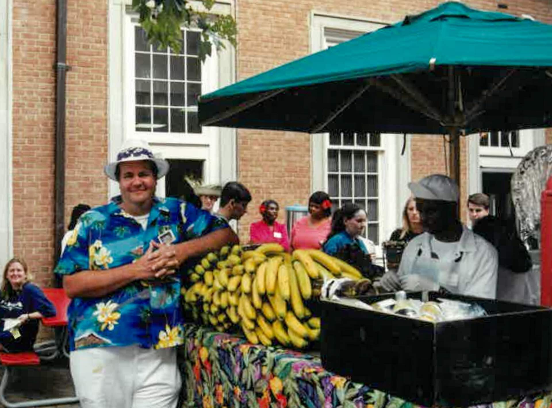 man in Hawaiian shirt poses at banana stand