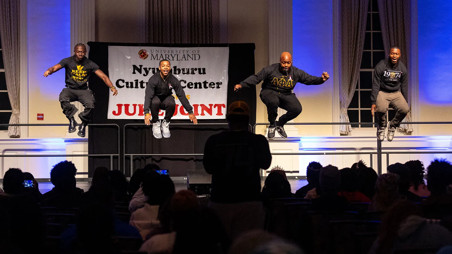 four young men jump on a stage