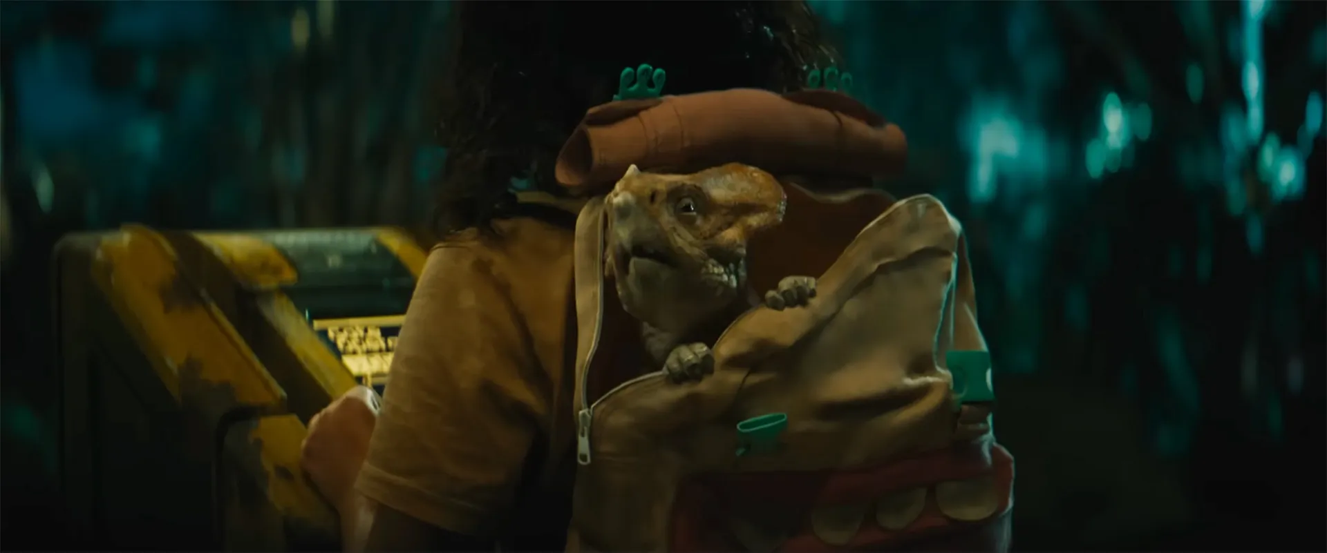 An Aquilops dinosaur sits in a backpack on a young girl's back