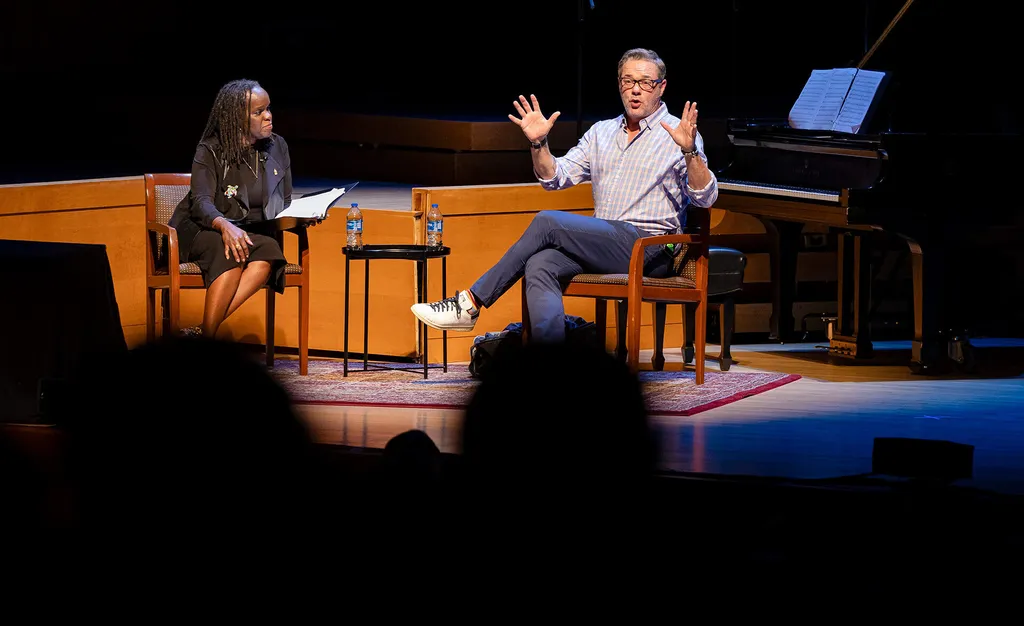 man and woman sit on a stage having a discussion