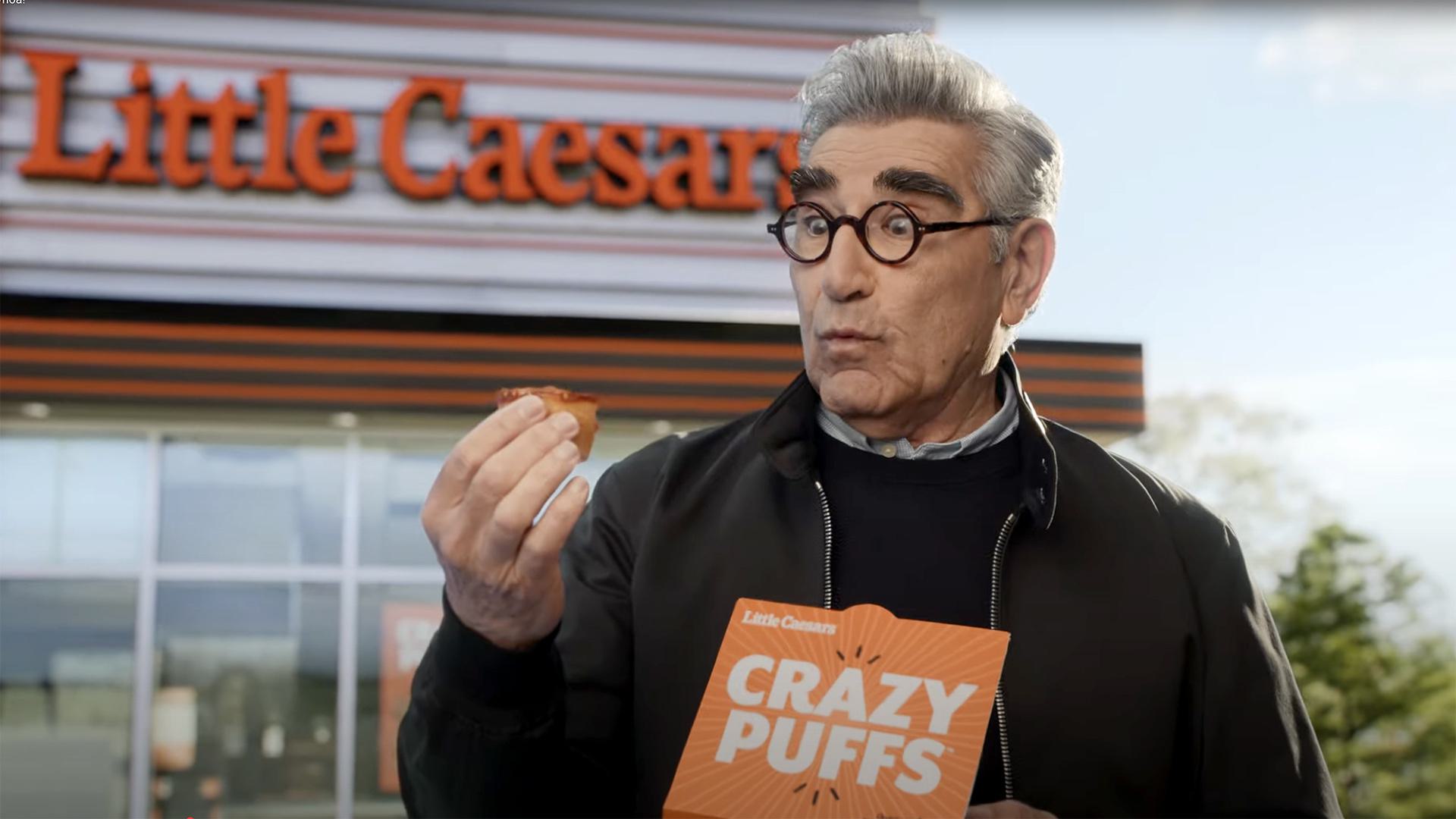 Eugene Levy holds Little Caesars Crazy Puff, looking surprised