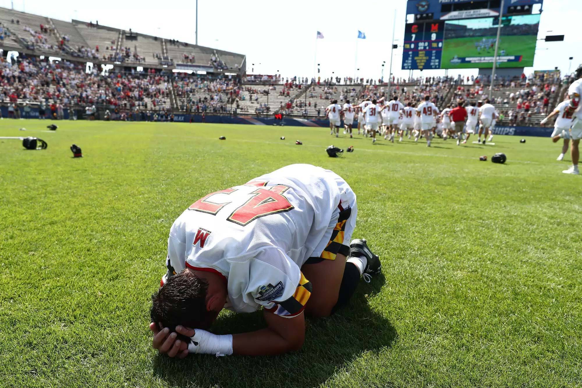 lacrosse player curls into ball on field, overcome with emotion