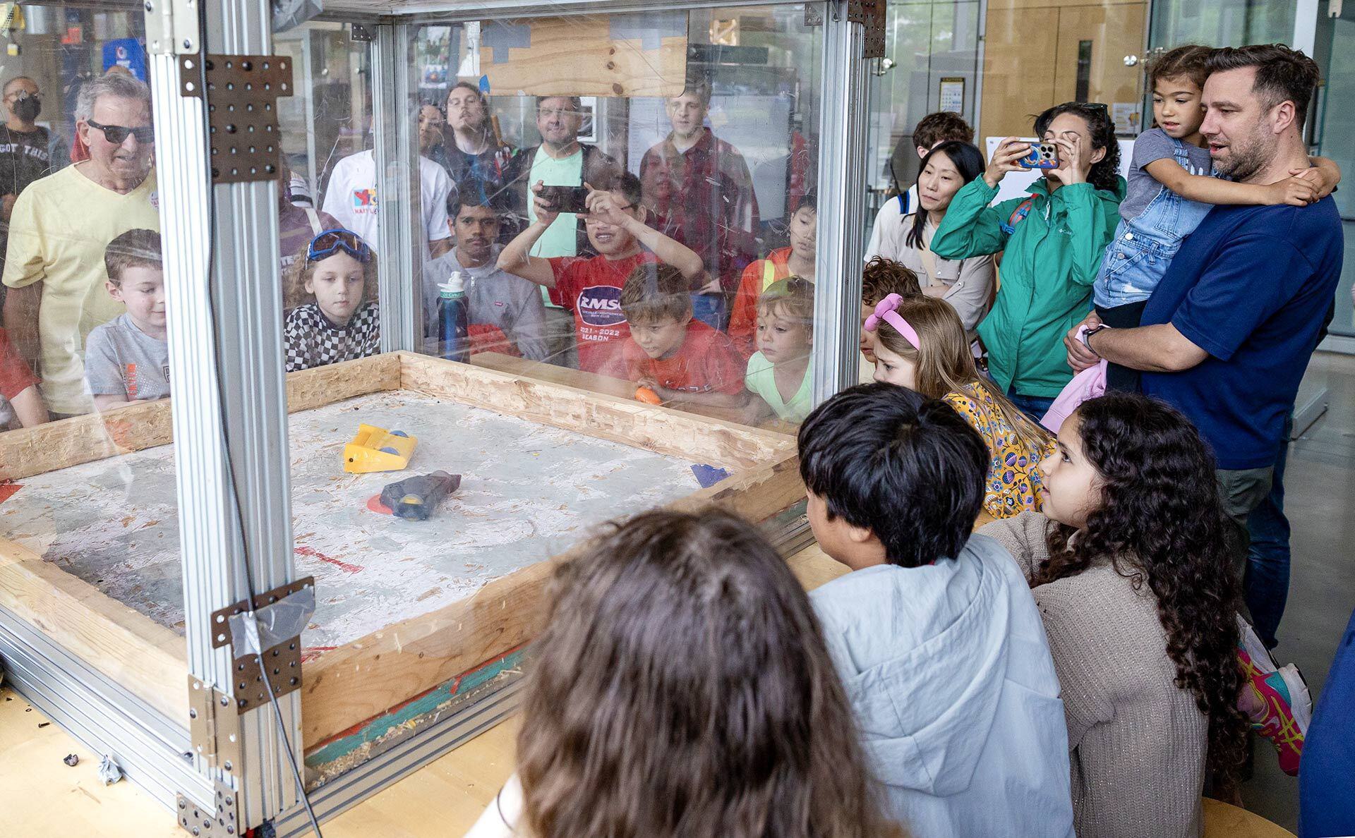 People watch small robots fight inside glass