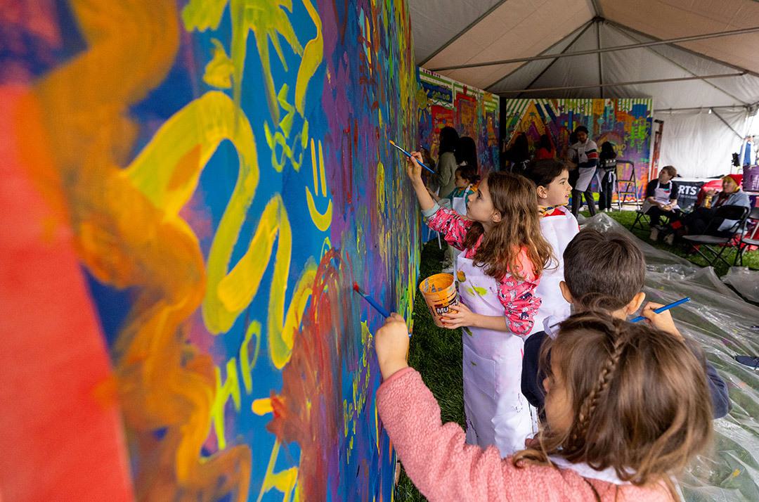 children paint on a colorful mural