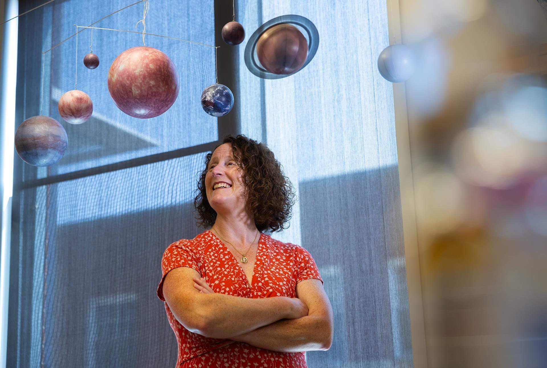 Melissa Hayes-Gerhke poses with model solar system hanging above her