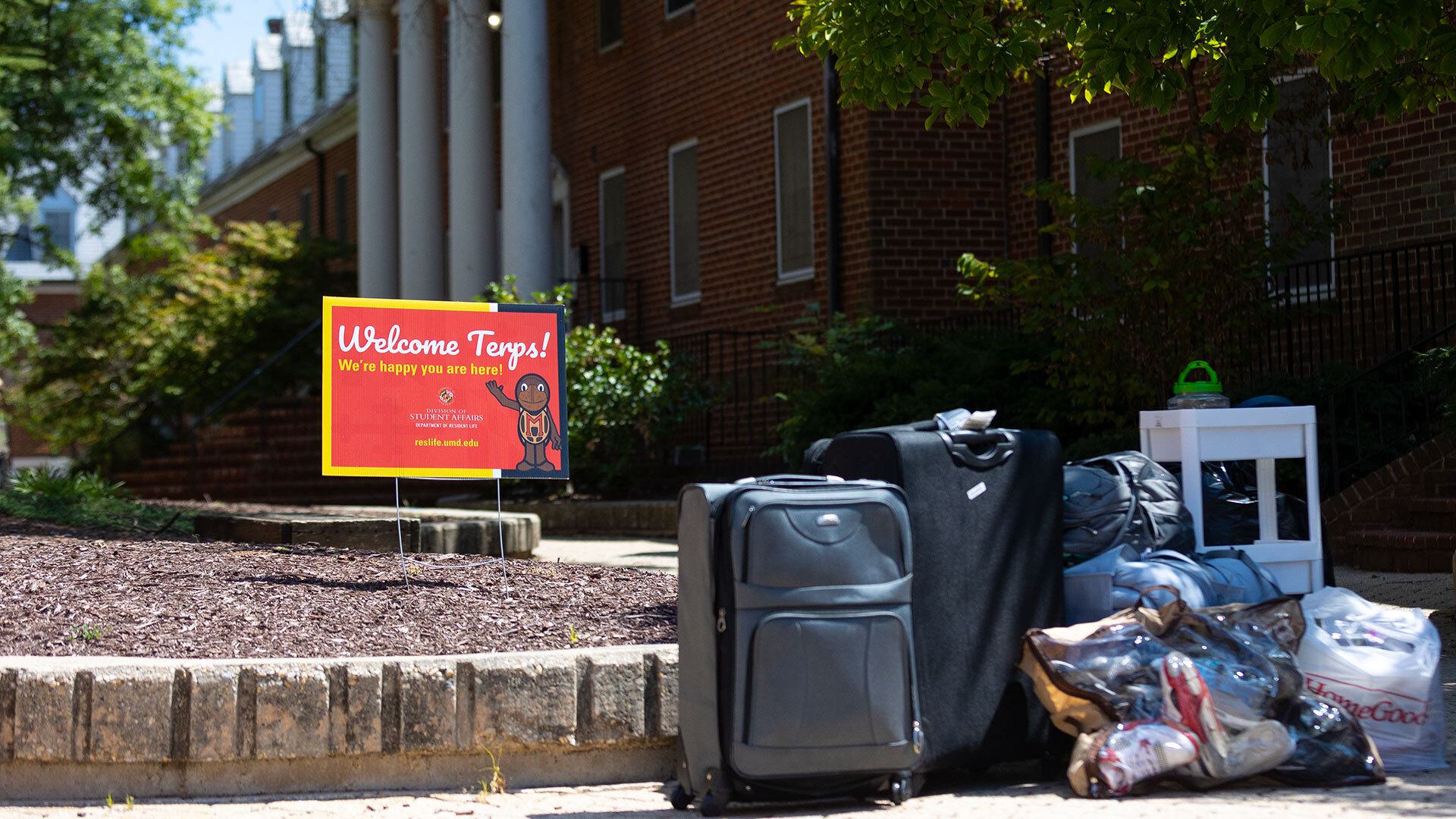 Luggage and furniture on the sidewalk next to a sign that says "Welcome Terps!"