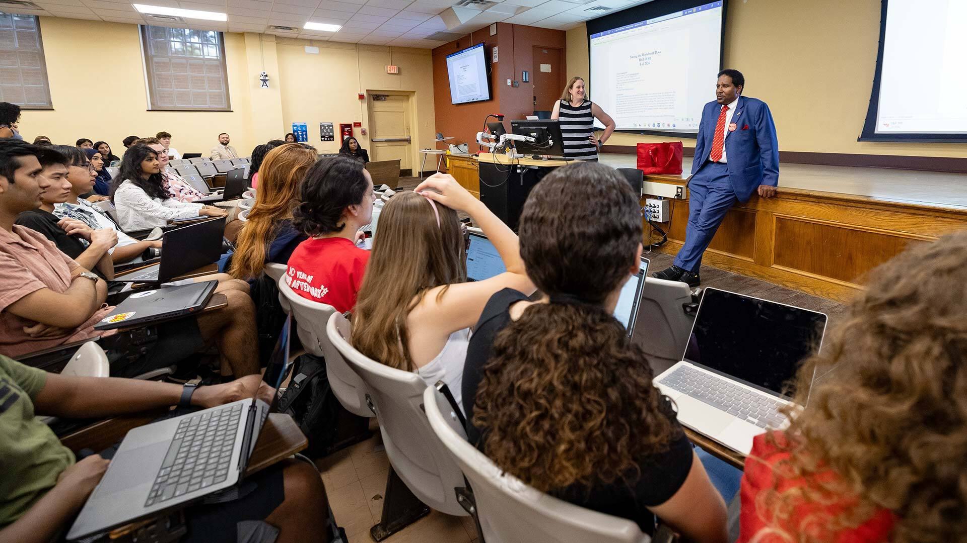 Pines stands at front of class with professor