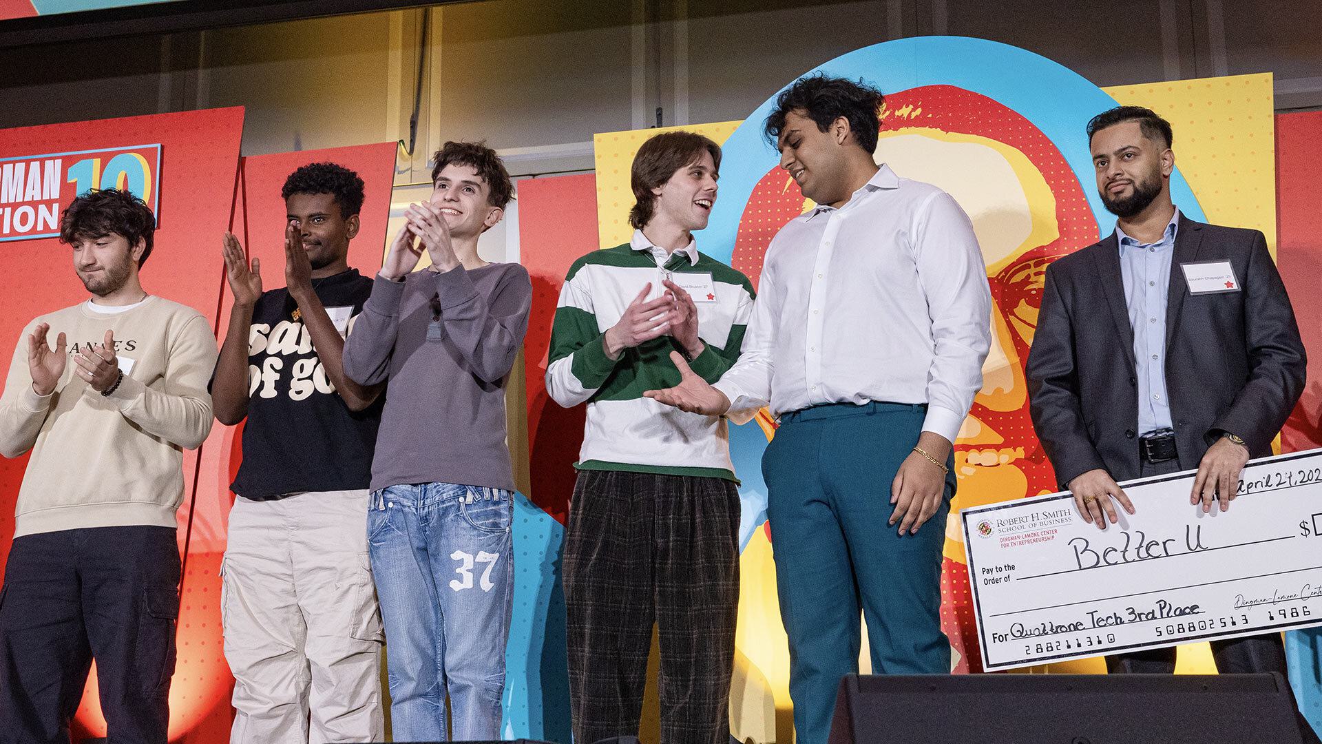Winners of a pitch competition stand next to each other on stage