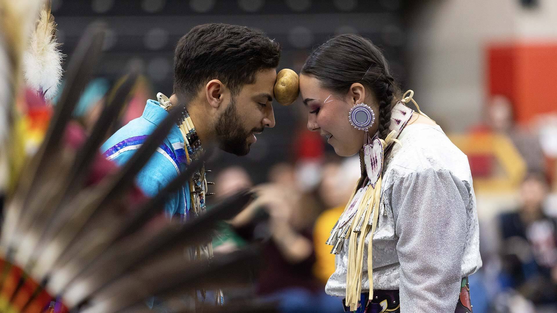 two people keep potato suspended between their foreheads