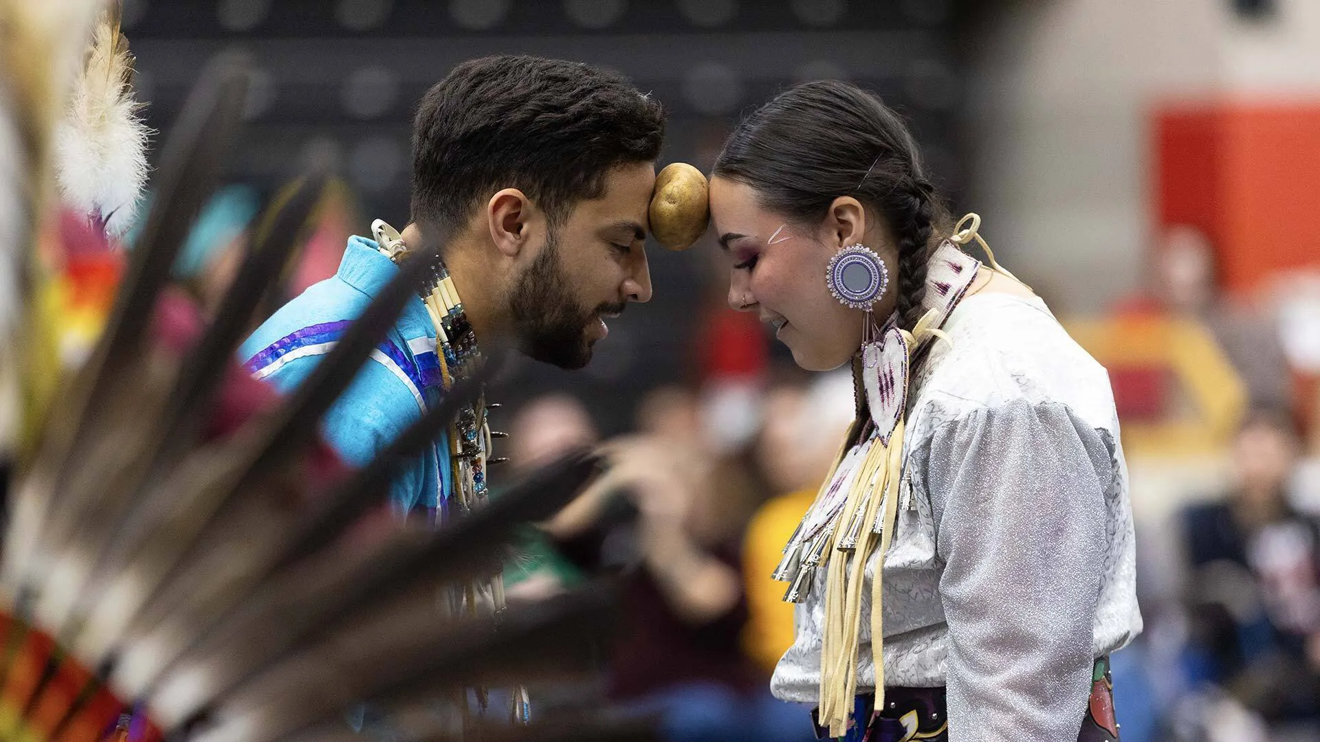 two people keep potato suspended between their foreheads