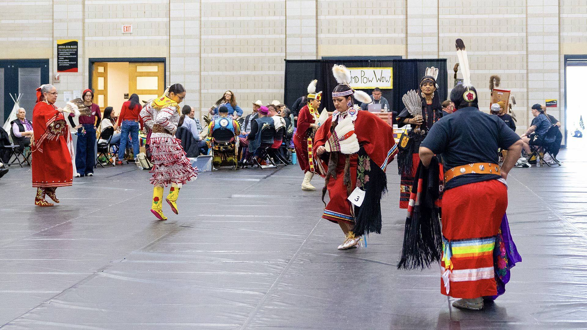 Female dancers dressed in red do a memorial dance