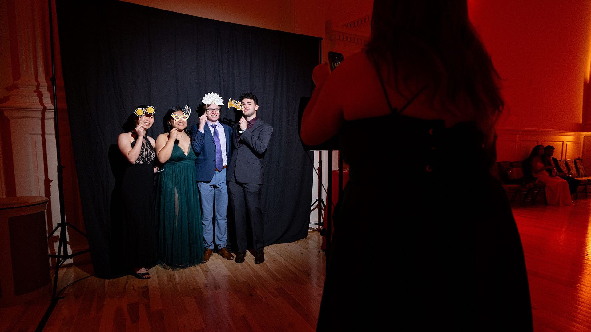 four people stand in front of a black backdrop having pictures taken