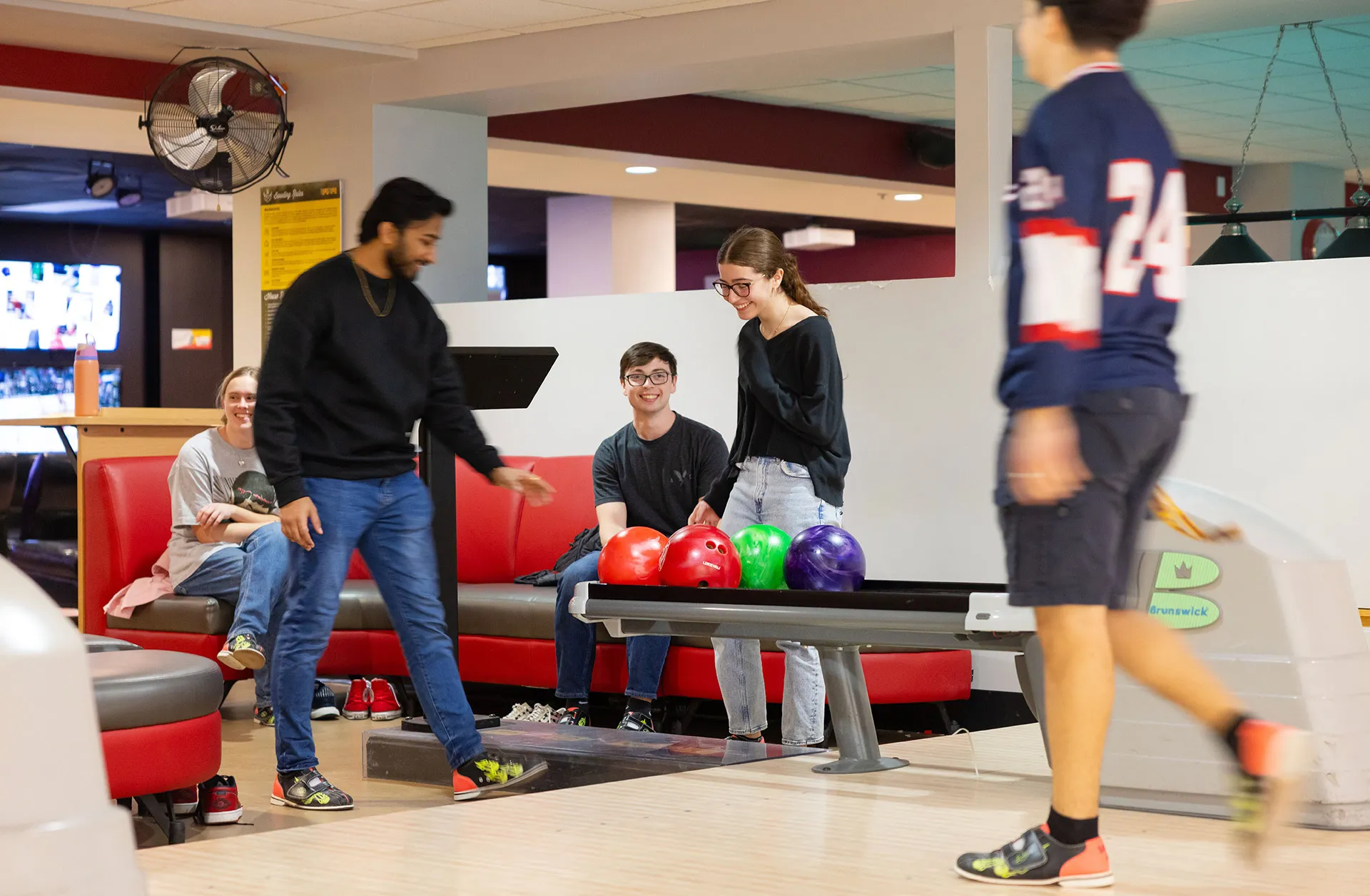 A group of students bowling with brightly colored balls