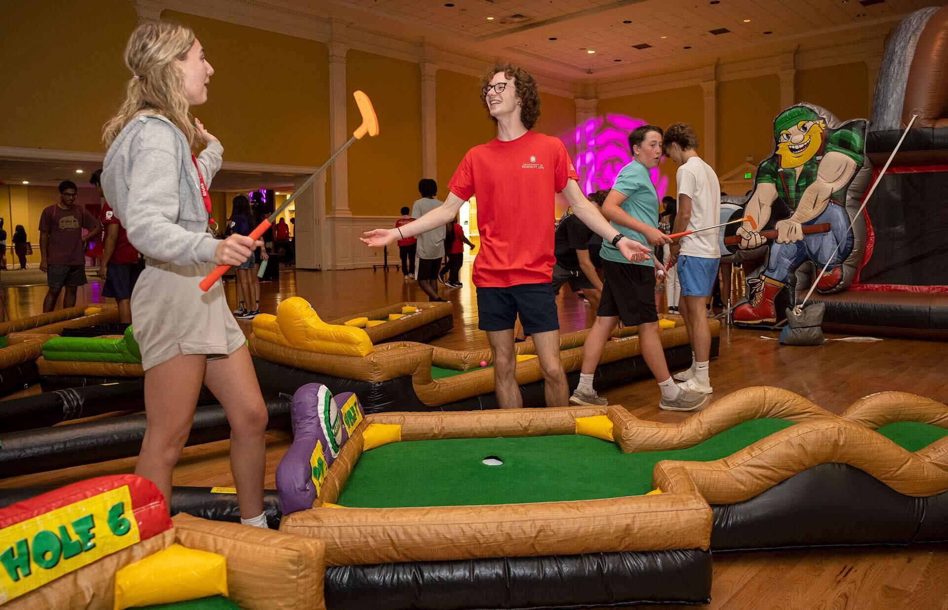 two students play mini golf in stamp student union
