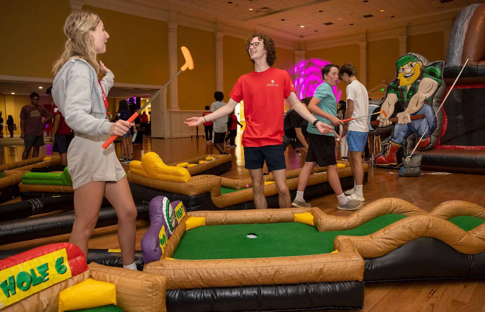 two students play mini golf in stamp student union