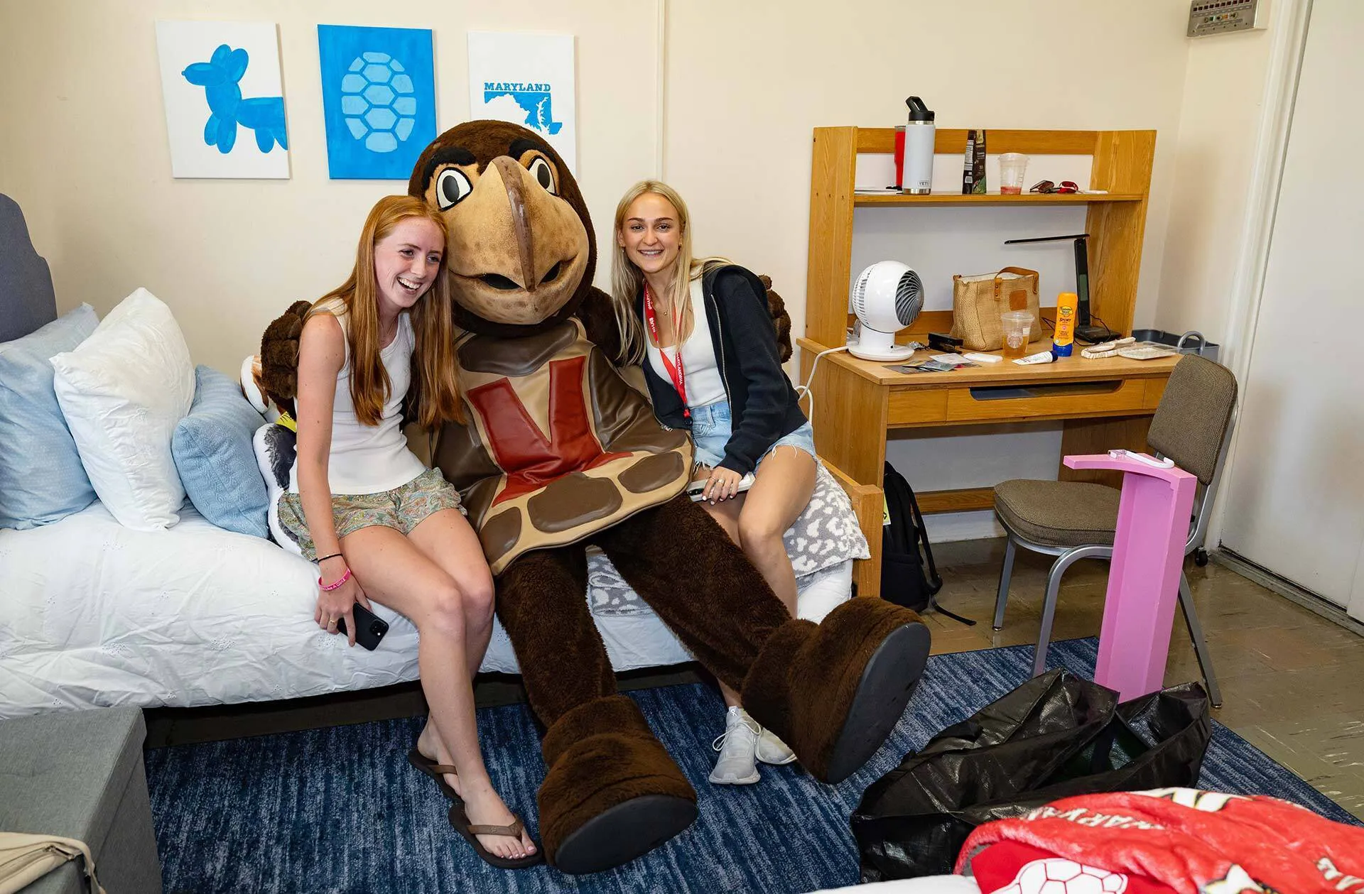 Female students pose in dorm room with mascot