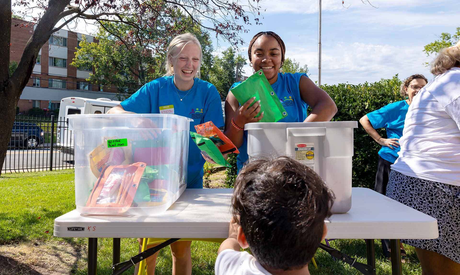 two students hand out school supplies