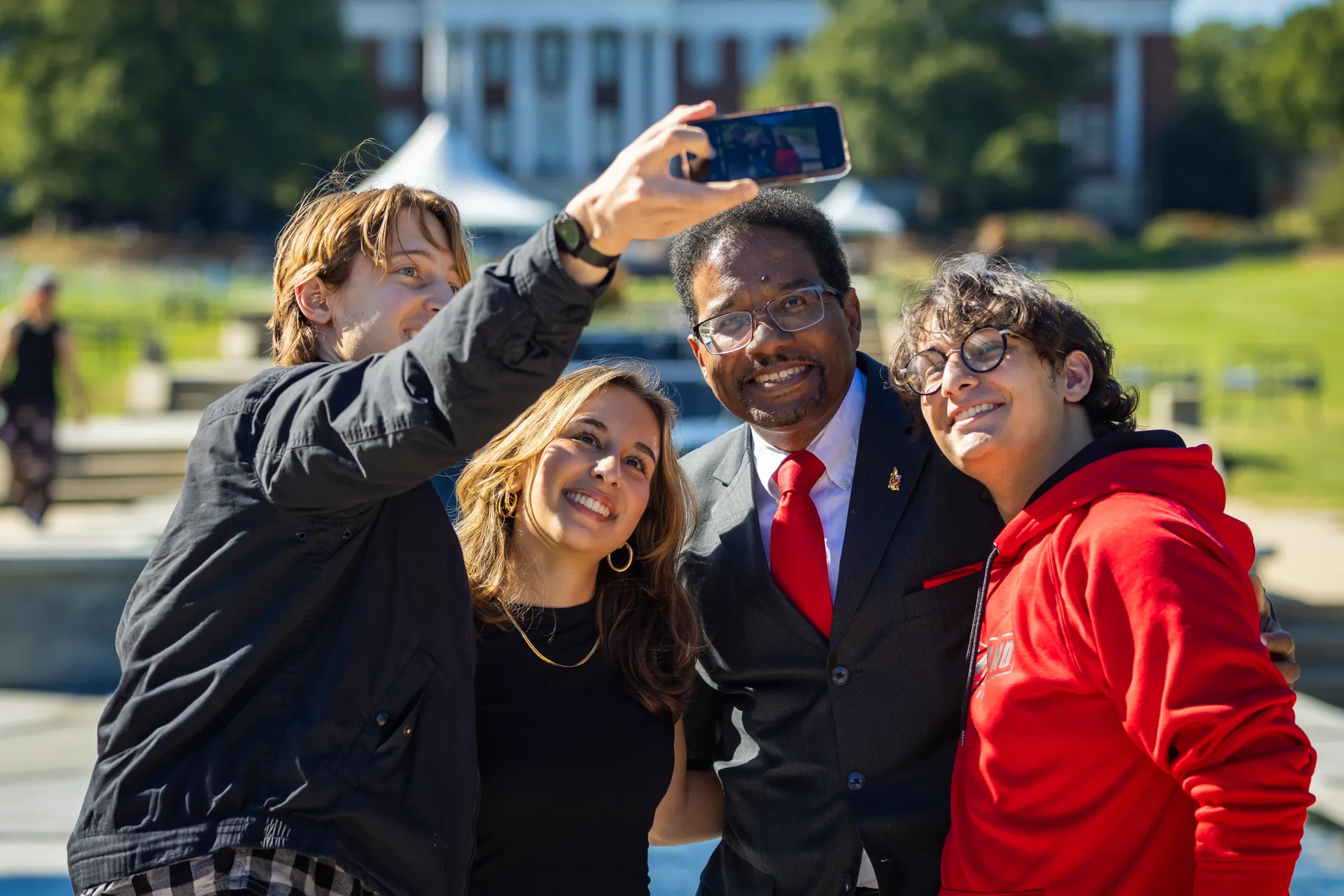 three men and a woman pose for a selfie