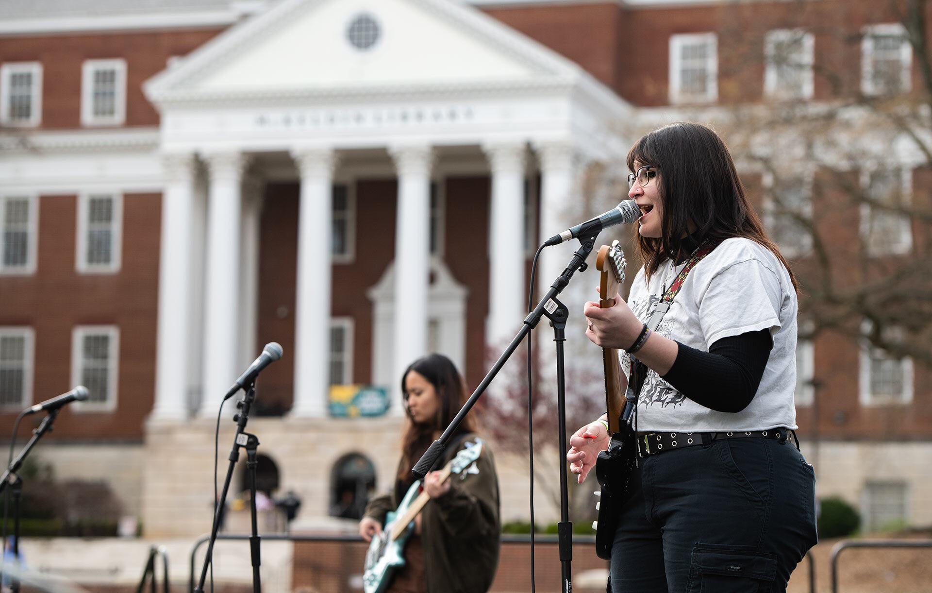 a woman palys a guitar and sings
