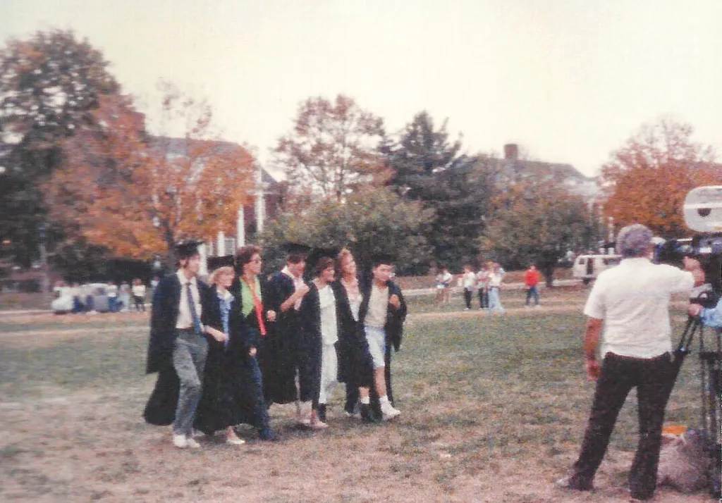 Brat Pack stars in graduation regalia walking across Frat Row while being filmed