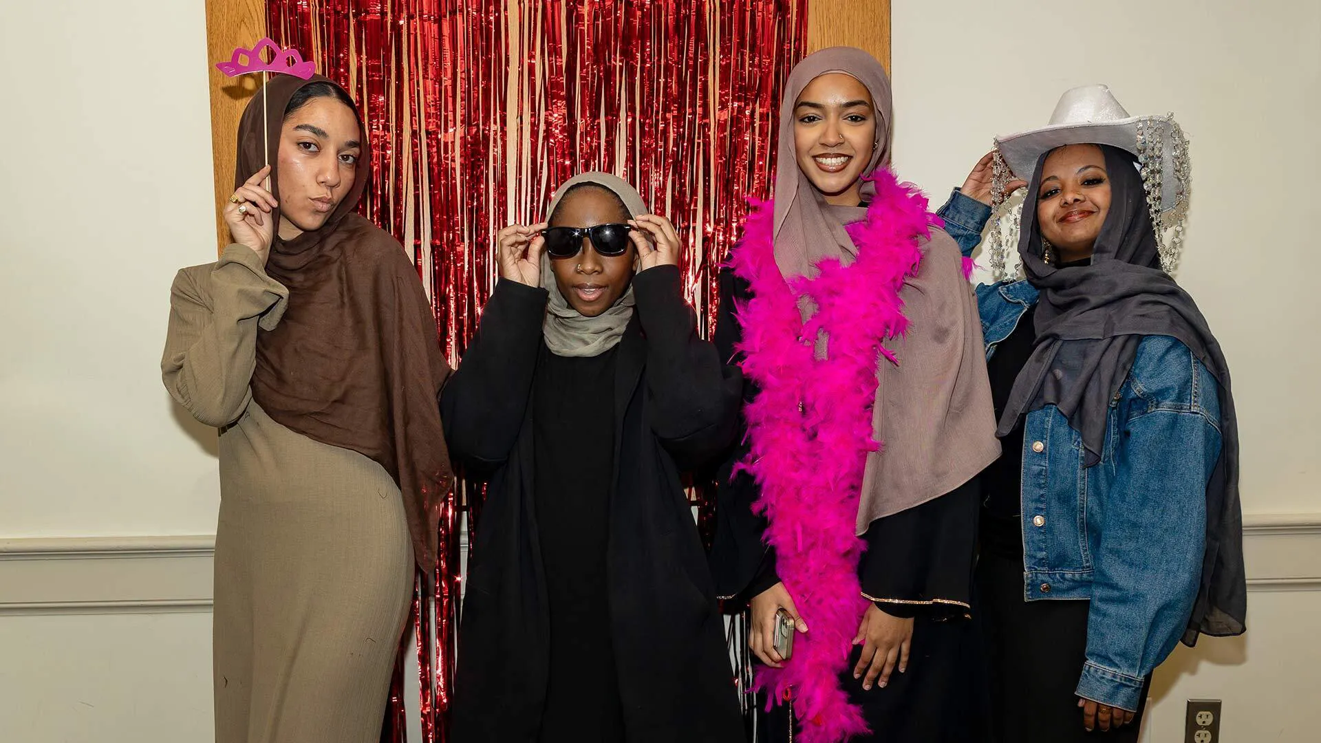 Four women pose in a fashion show-like environment