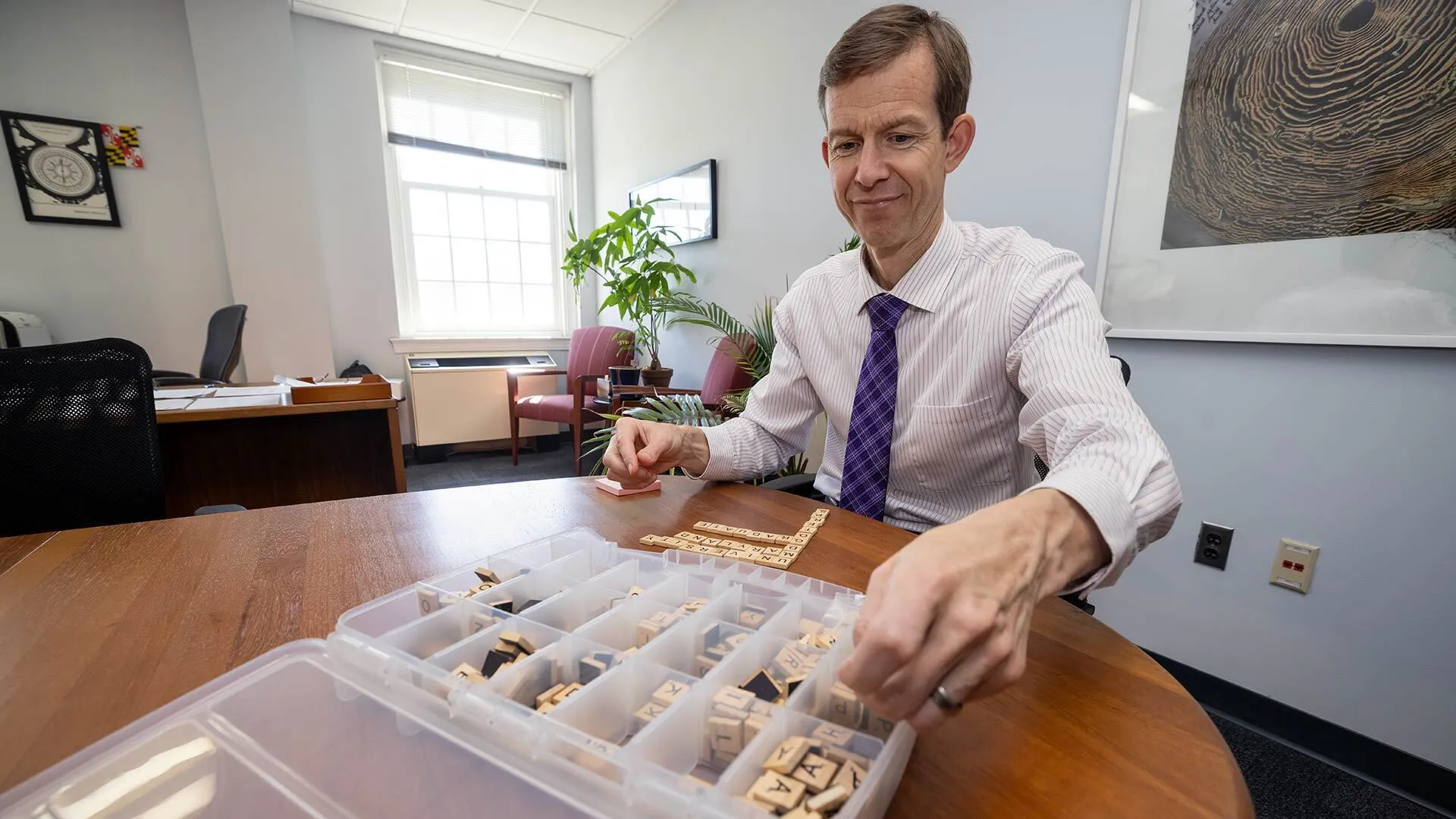man messes with scrabble tiles in a box