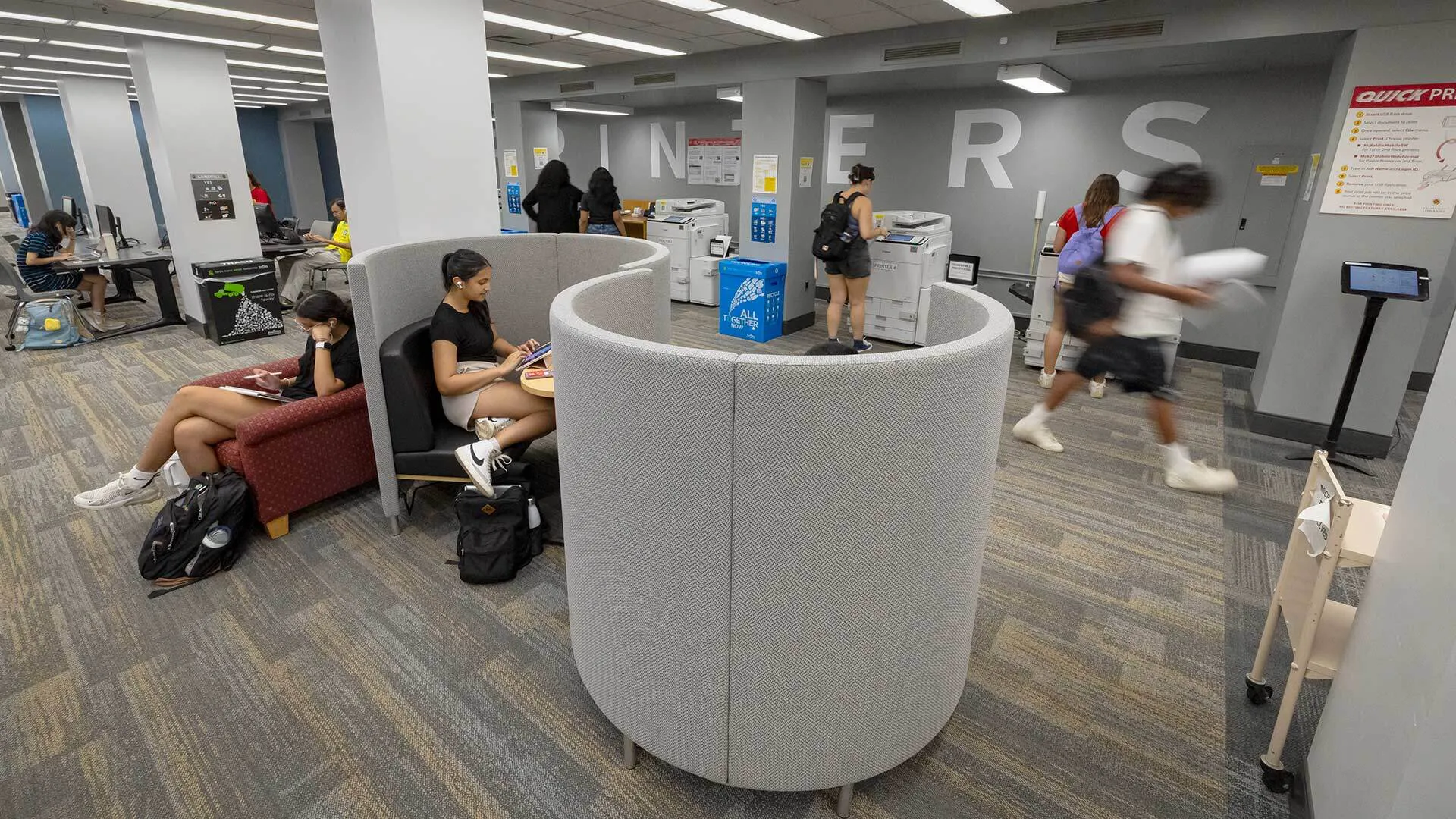 Students studying in the library in an "S"-shaped gray pod