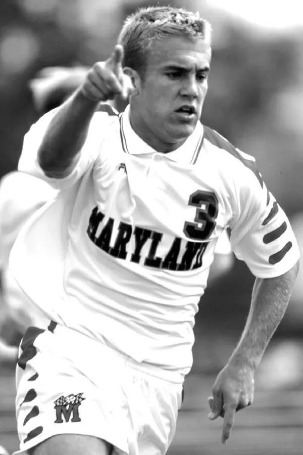 Black and white photo of male soccer player running and pointing
