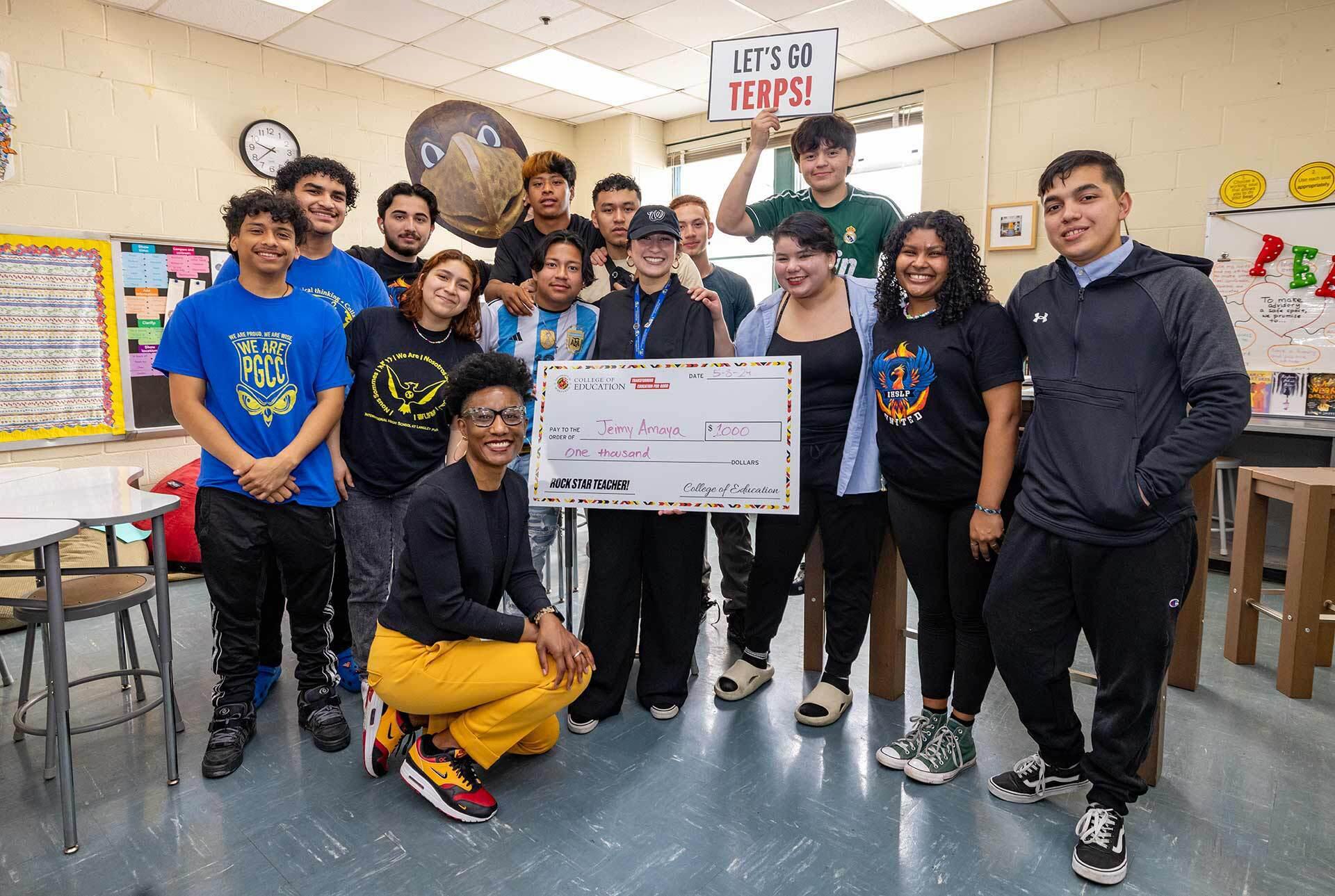 students, teacher and UMD College of Education pose with giant check