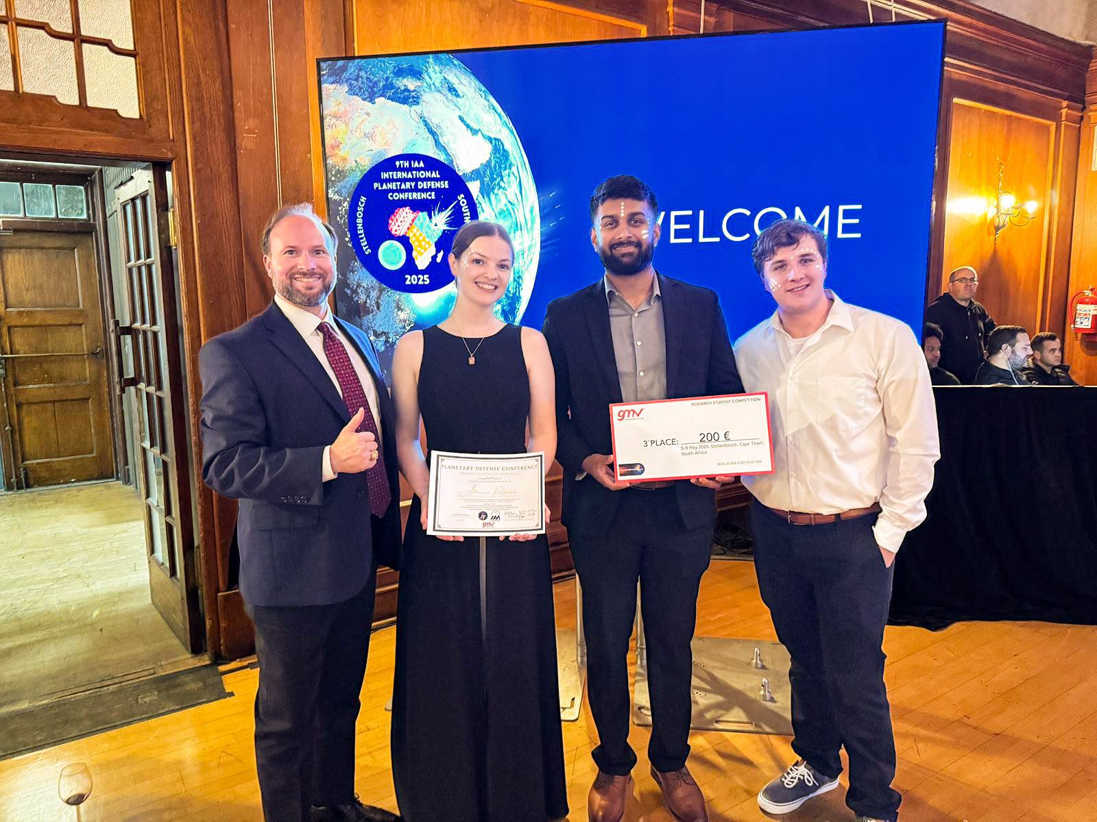 four team members pose with certificates