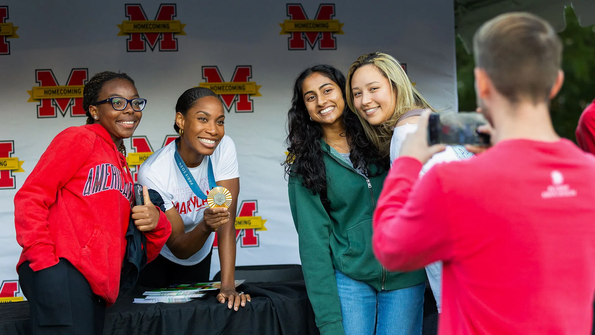 person with gold medal poses with three others at a table