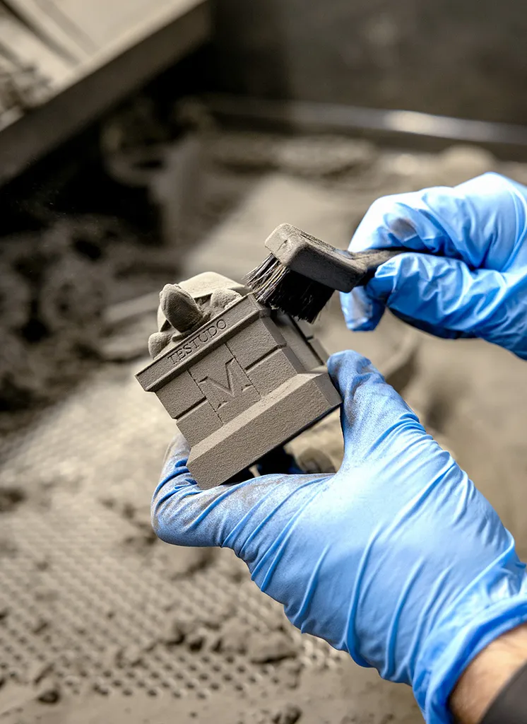 gloved hands brush off powder from 3D-printed Testudo statue