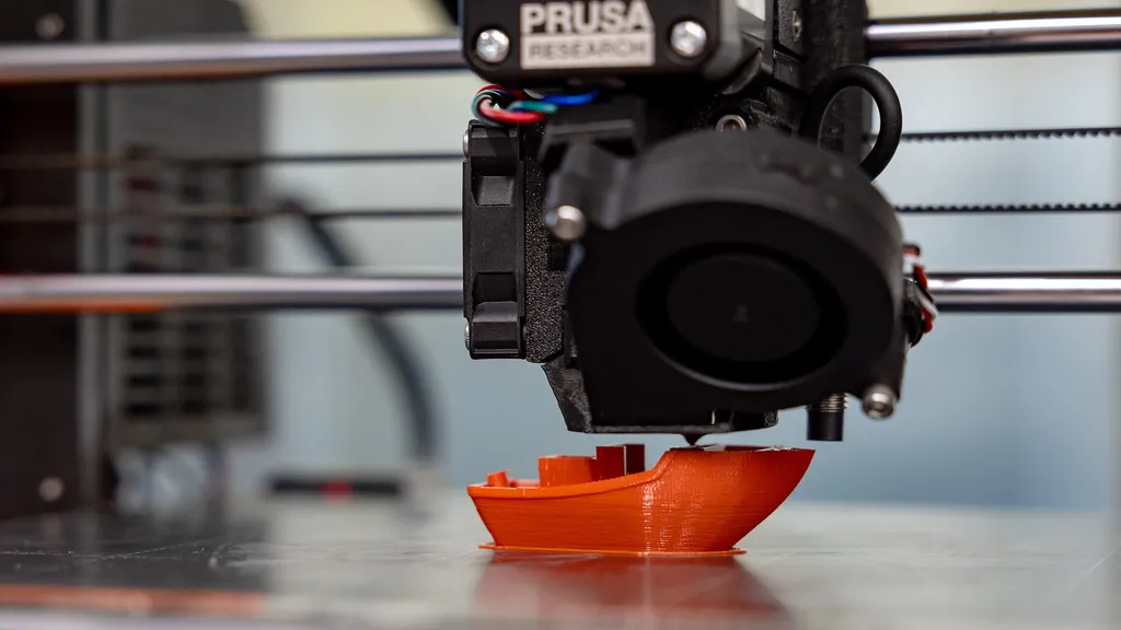 A 3D filament printer in the process of printing an orange boat
