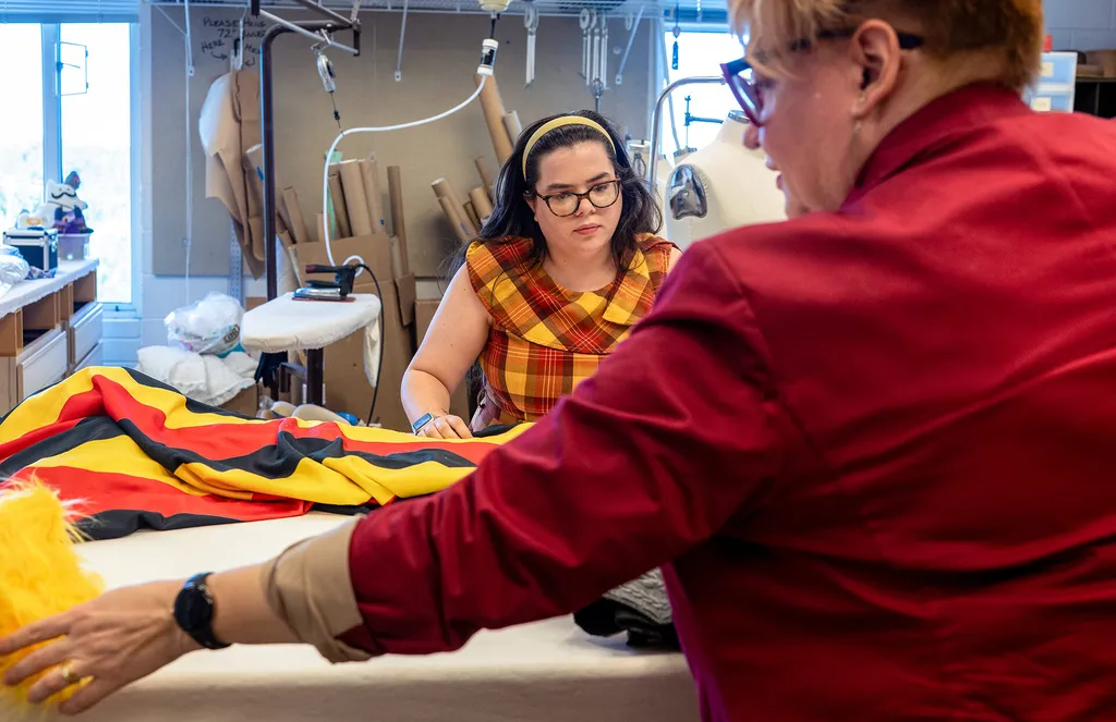 two people work with red, black and gold fabric