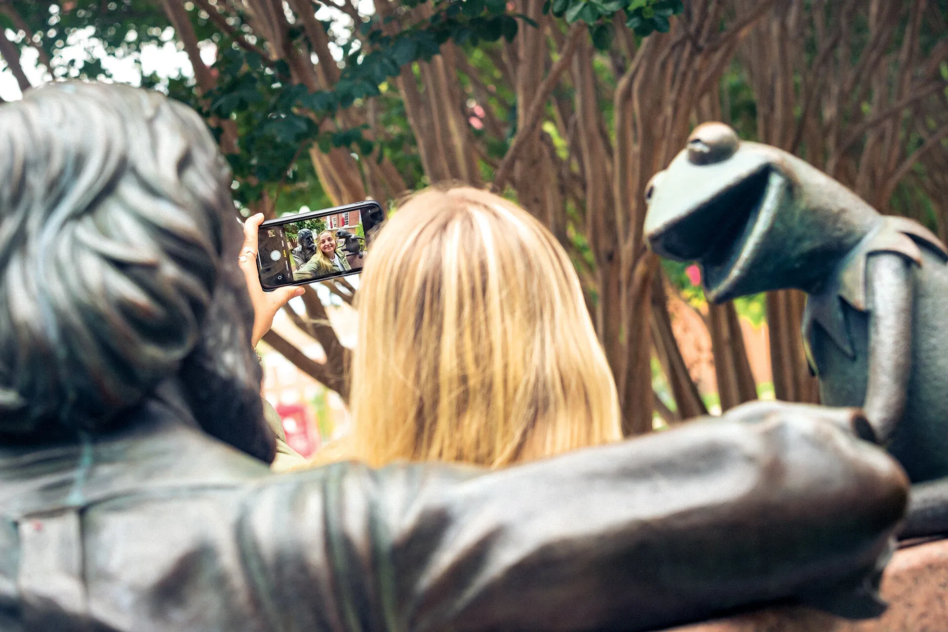 student takes a selfie at Jim Henson statue