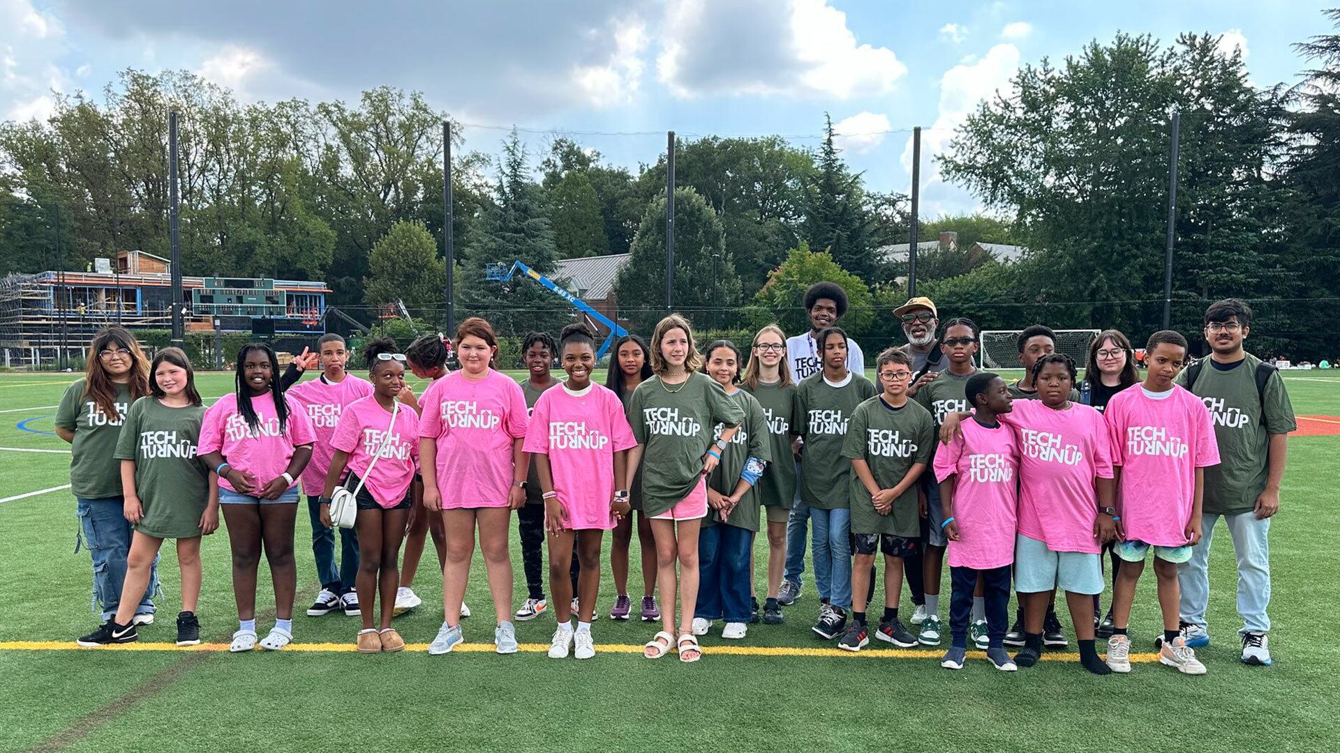 Students in pink and green Tech Turn Up shirts on a field